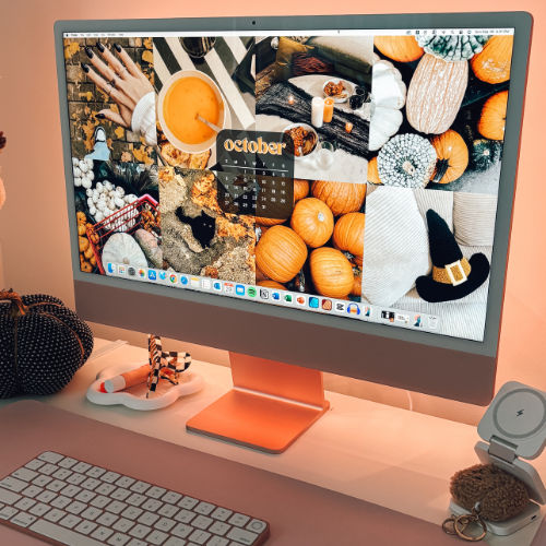 Stylish desktop setup featuring an iMac displaying a cozy October-themed collage with pumpkins and fall decor, set in a warm, orange-lit workspace.