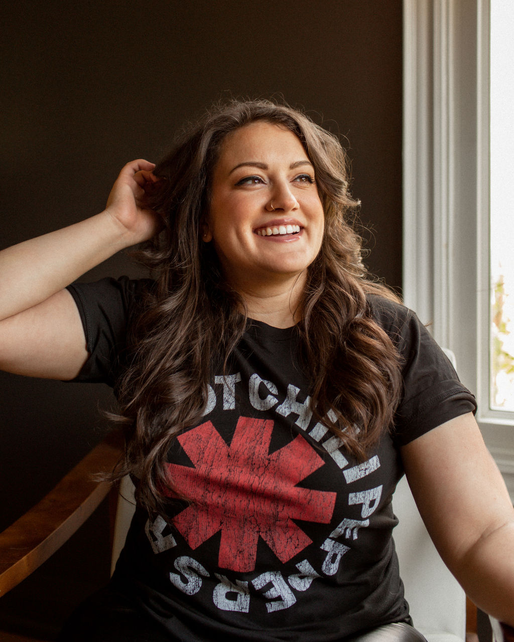 Chantel Bettencourt, web designer in Toronto, smiling by a window, wearing a Red Hot Chili Peppers T-shirt.