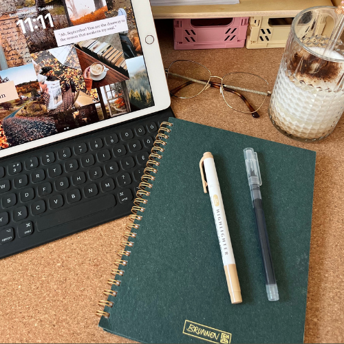 Workspace setup with a tablet displaying design inspiration, a notebook, pens, and a coffee, illustrating a guide for uploading custom fonts in Flodesk by a web designer in Toronto, Canada.