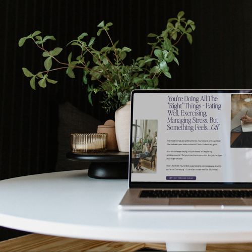 Laptop displaying a wellness-focused website design, created by a web designer in Canada, set on a table with a plant and decor