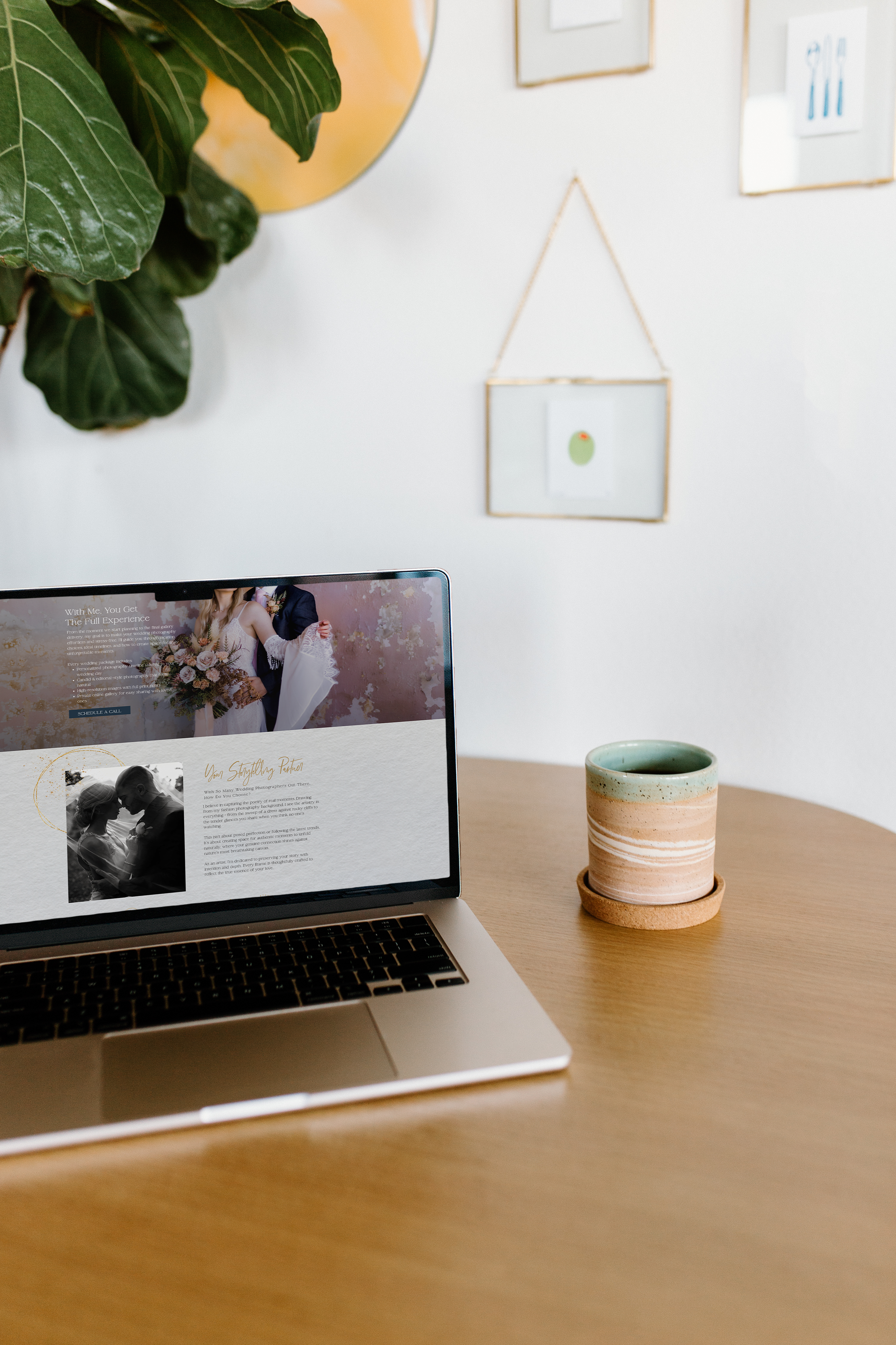 Laptop on a wooden table displaying a wedding-themed Showit website with a custom design, next to a ceramic mug and modern decor in a bright Toronto workspace.